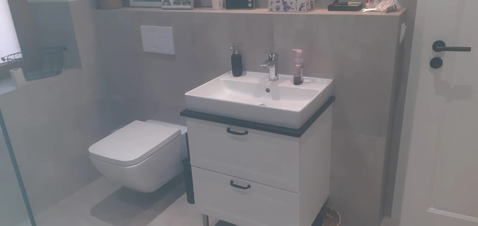 Waschtisch mit Unterschrank neben Wand-WC, darüber eine durchgehende Ablage